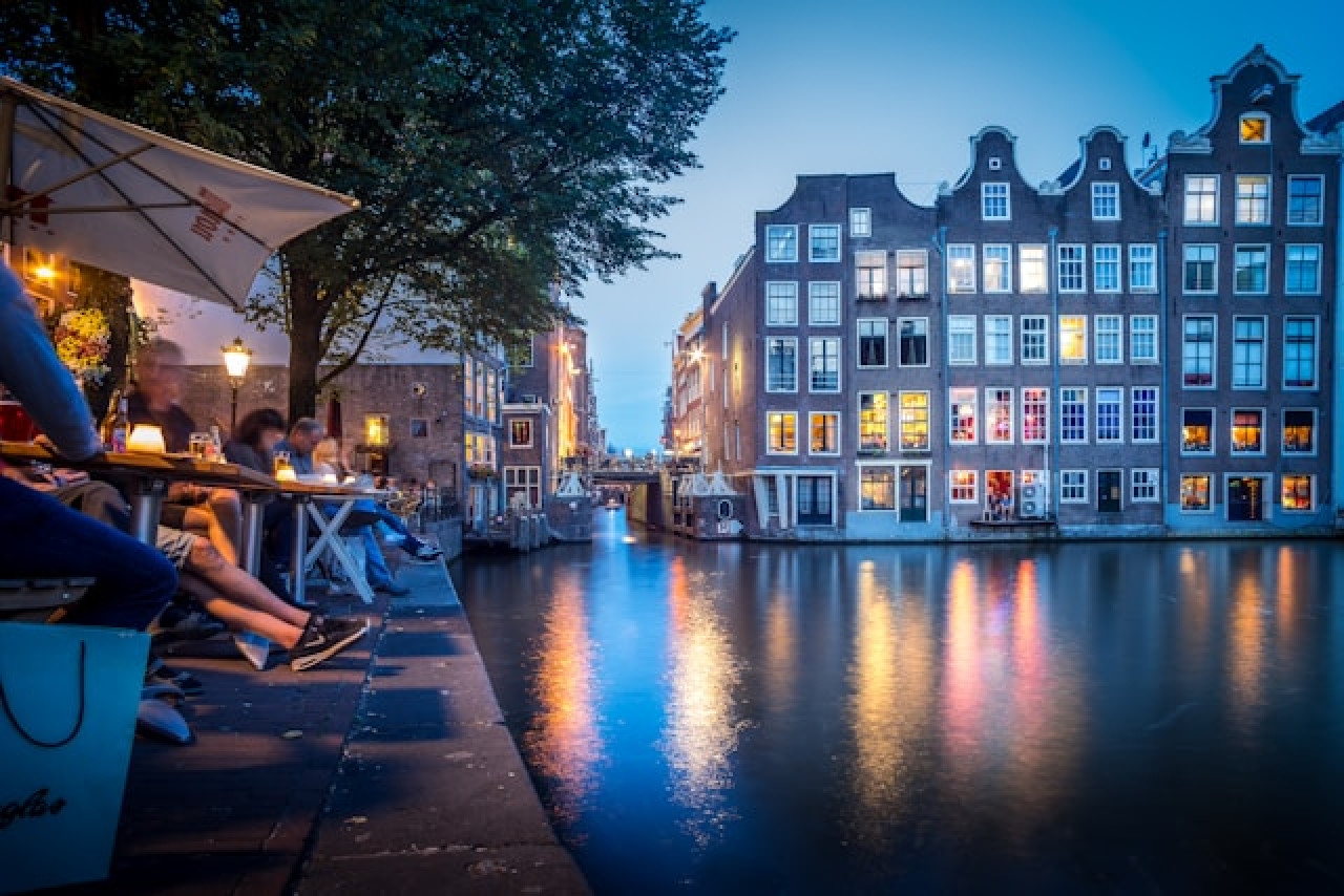 Dutch houses on a canal and people sitting outside by night. Dutch houses on a canal and people sitting outside by night.